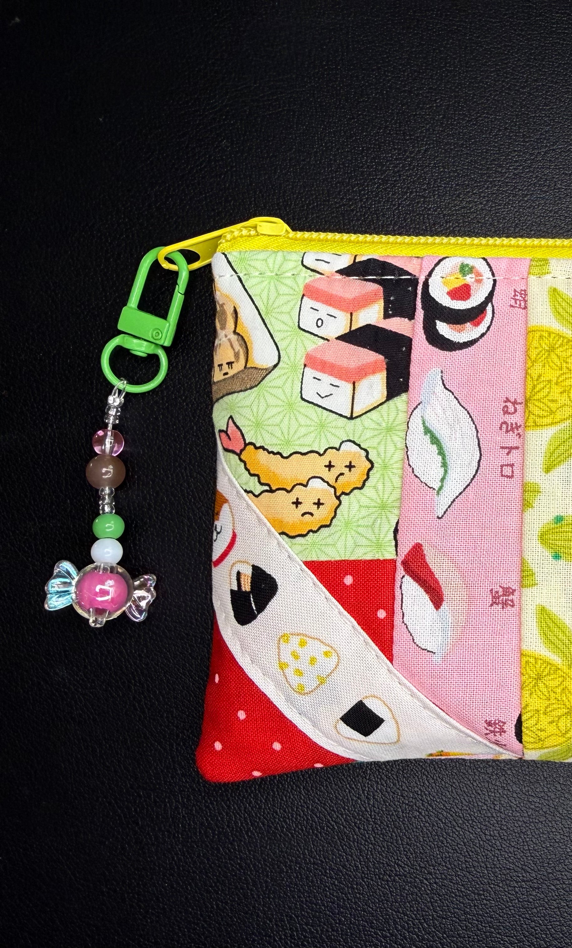 Colorful pouch with sushi-themed design and keychain on a black background
