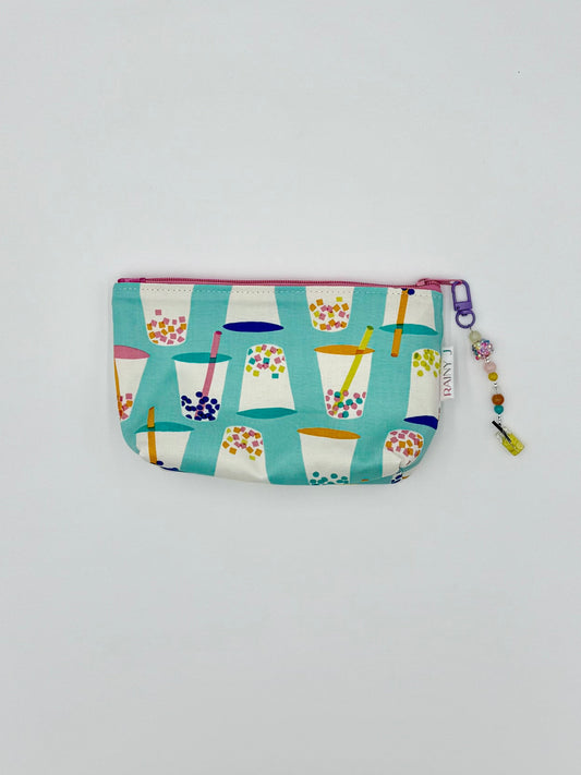 zippered toiletry bag with boba print on an aqua background with a kawaii charm